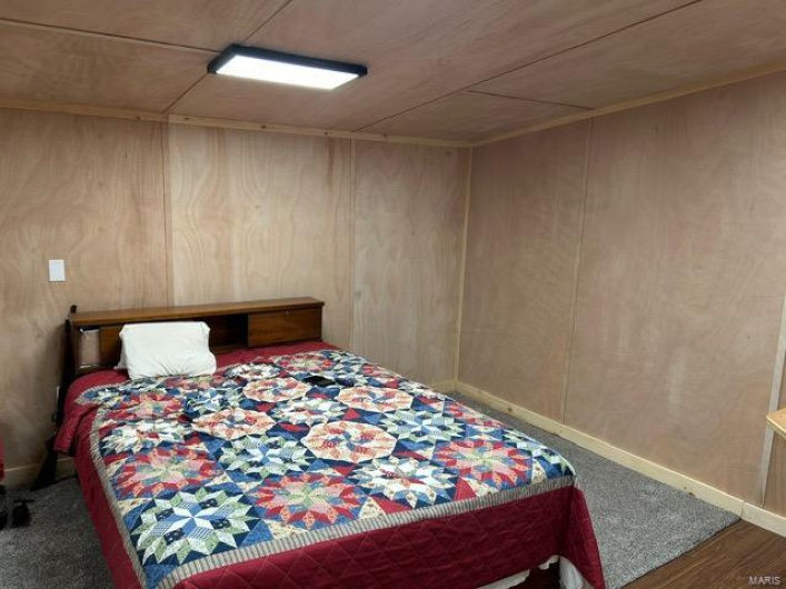 Bedroom featuring baseboards and wood walls