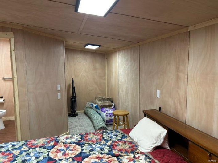 Carpeted bedroom featuring wood walls and ensuite bathroom