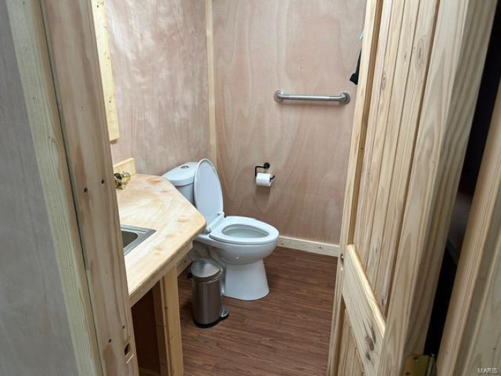 Half bath featuring wood finished floors, vanity, and toilet