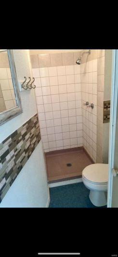 Bathroom featuring tile patterned floors, tiled shower, and toilet