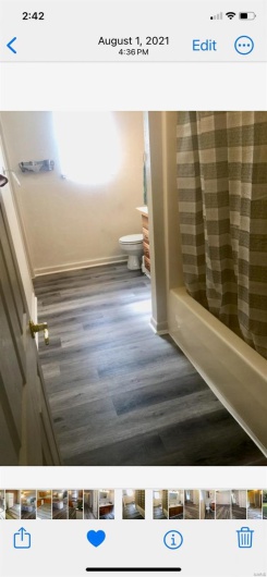 Bathroom featuring shower / bath combination with curtain, hardwood / wood-style flooring, and toilet