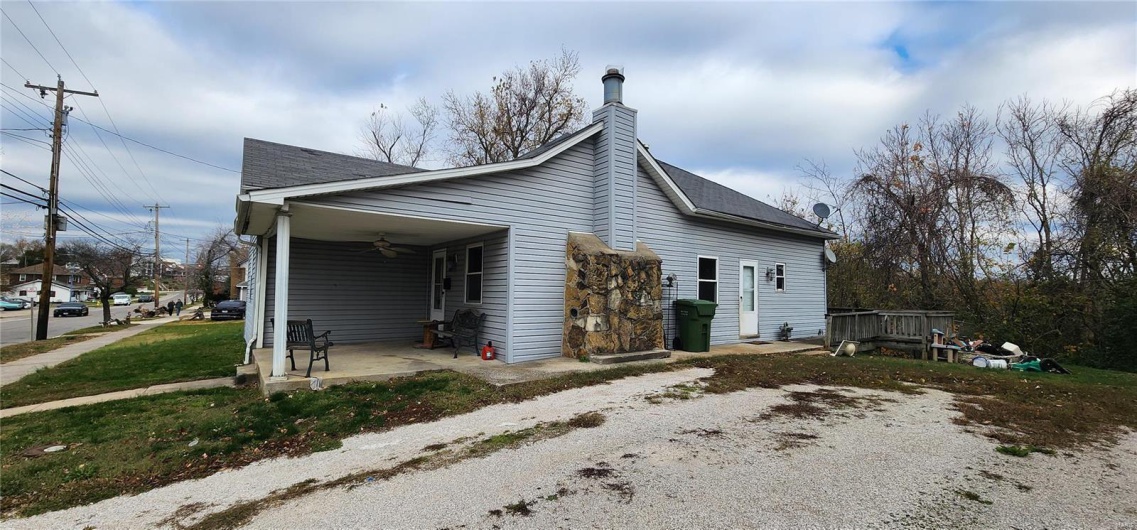 View of side of property featuring ceiling fan and a yard