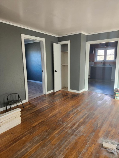Unfurnished bedroom featuring ornamental molding, hardwood / wood-style floors, a sink, and baseboards