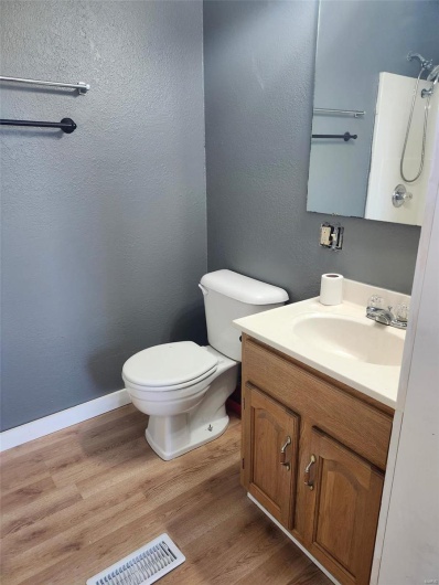 Bathroom with toilet, visible vents, wood finished floors, and vanity