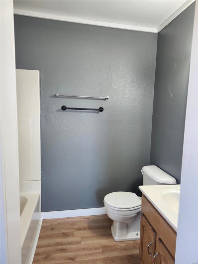 Full bathroom with toilet, baseboards, wood finished floors, and vanity