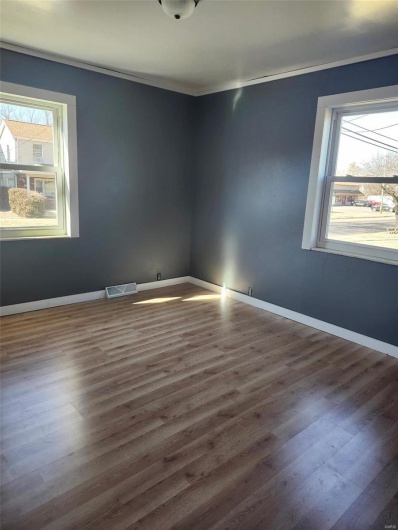 Empty room featuring a wealth of natural light, wood finished floors, visible vents, and baseboards