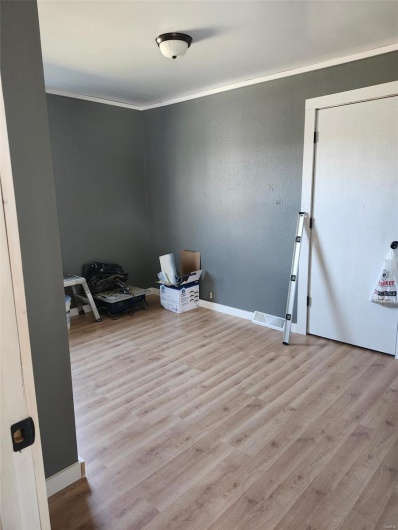 Unfurnished room with a textured wall, crown molding, baseboards, and wood finished floors