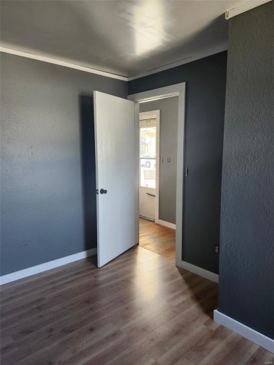 Unfurnished room featuring a textured wall, baseboards, and wood finished floors