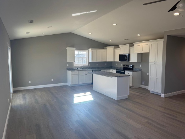 Kitchen featuring white cabinets, a center island, dark hardwood / wood-style flooring, and appliances with stainless steel finishes