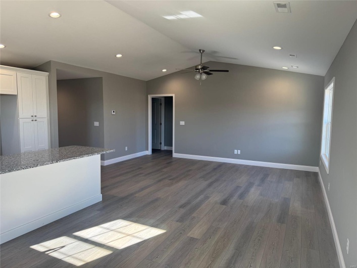 Unfurnished living room featuring dark hardwood / wood-style floors, ceiling fan, and lofted ceiling