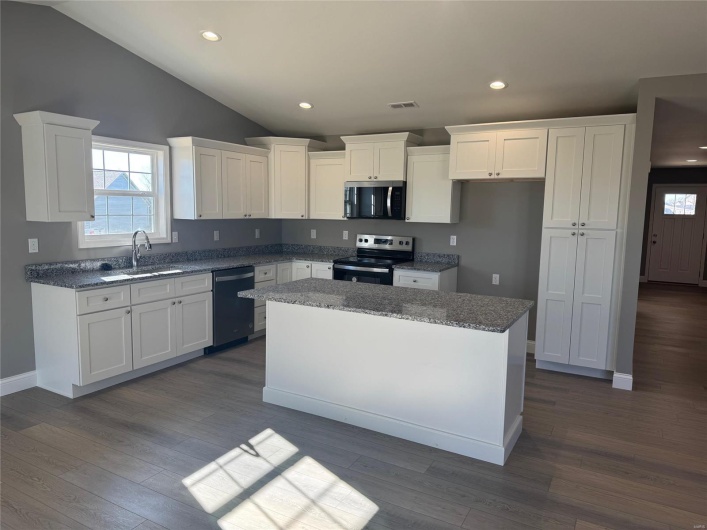 Kitchen with sink, dark hardwood / wood-style floors, a kitchen island, white cabinetry, and stainless steel appliances