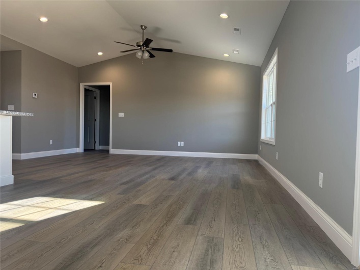 Unfurnished living room featuring ceiling fan, dark wood-type flooring, and vaulted ceiling