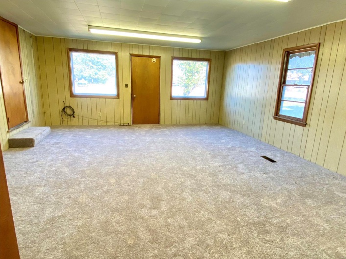 Unfurnished room featuring wood walls and carpet