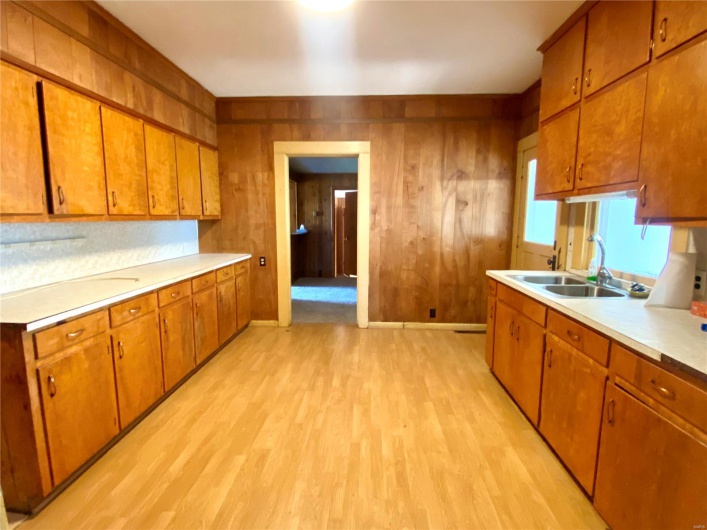 Kitchen featuring light wood-type flooring, wood walls, and sink