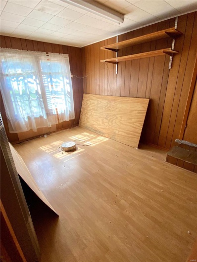 Spare room featuring light wood-type flooring and wooden walls