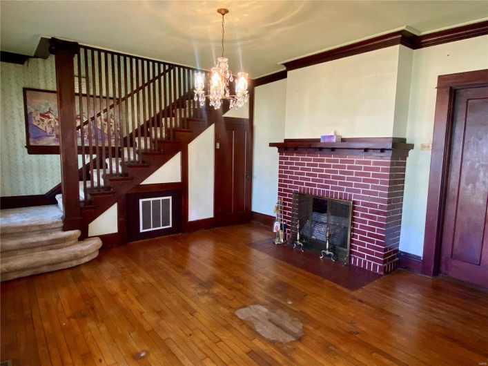 Unfurnished living room with a notable chandelier, a fireplace, ornamental molding, and hardwood / wood-style flooring