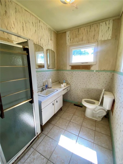Bathroom featuring tile patterned floors, a shower with shower door, vanity, and toilet