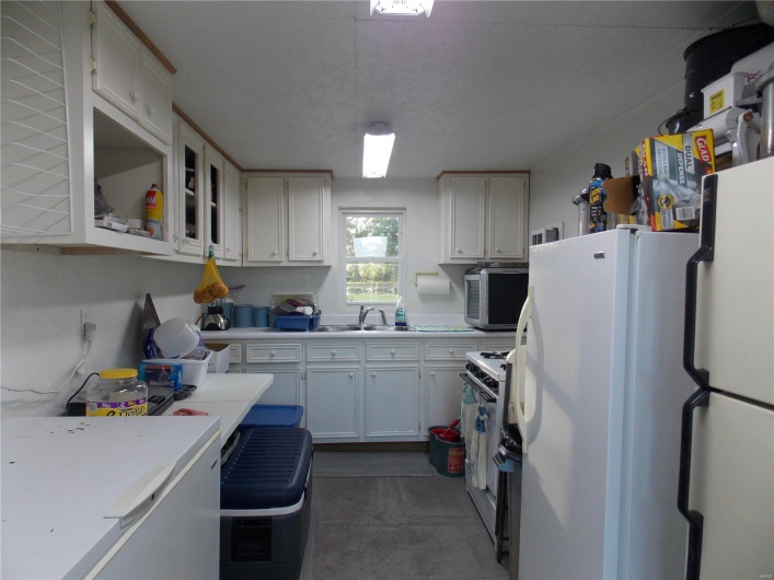 Kitchen featuring hanging light fixtures, white appliances, sink, and white cabinets