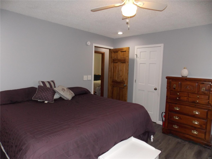Bedroom featuring dark hardwood / wood-style flooring, ceiling fan, and a textured ceiling
