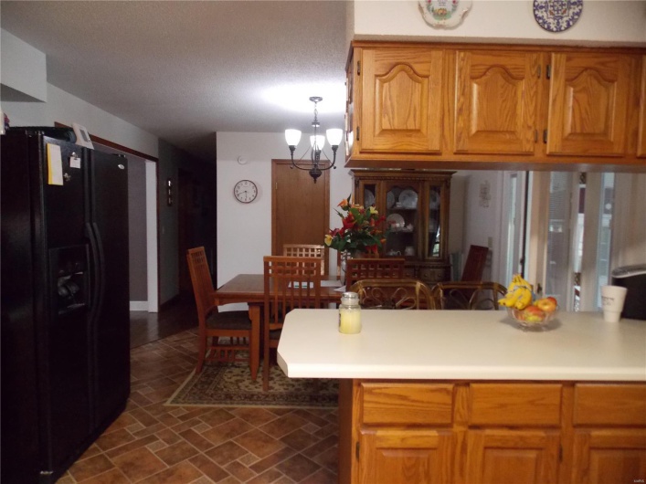 Kitchen featuring a textured ceiling, black fridge with ice dispenser, kitchen peninsula, and a notable chandelier