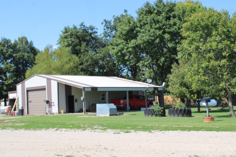 View of outdoor structure with a lawn, a carport, and a garage
