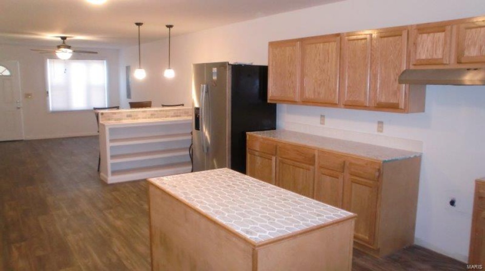 Kitchen with stainless steel fridge, dark hardwood / wood-style flooring, ceiling fan, a kitchen island, and hanging light fixtures