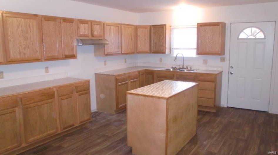 Kitchen with dark hardwood / wood-style floors, a center island, sink, and light brown cabinetry