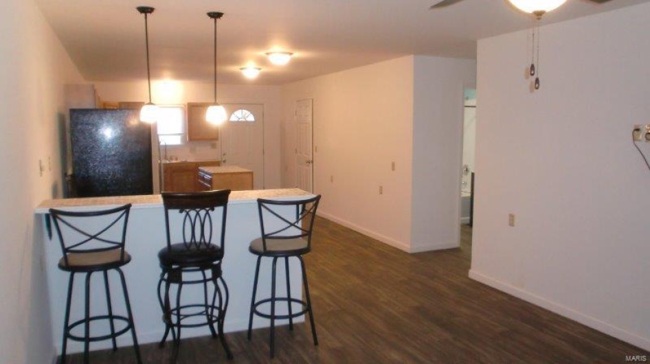 Kitchen featuring kitchen peninsula, dark hardwood / wood-style flooring, black fridge, ceiling fan, and decorative light fixtures