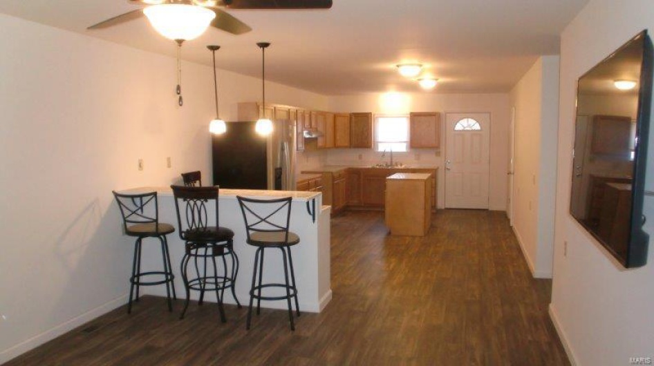 Kitchen featuring stainless steel refrigerator, sink, dark wood-type flooring, kitchen peninsula, and decorative light fixtures