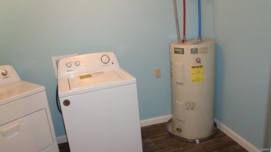 Clothes washing area featuring washer and clothes dryer, dark wood-type flooring, and water heater