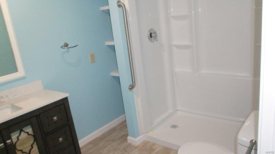 Bathroom featuring a shower, wood-type flooring, vanity, and toilet