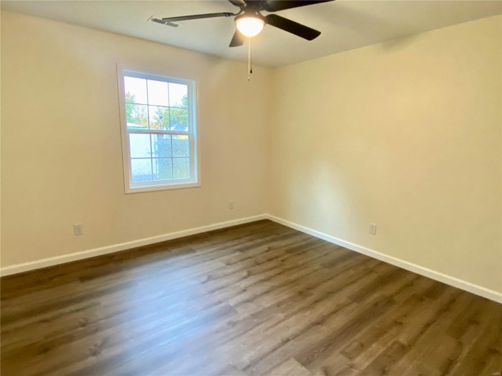 Spare room with dark wood-type flooring and ceiling fan