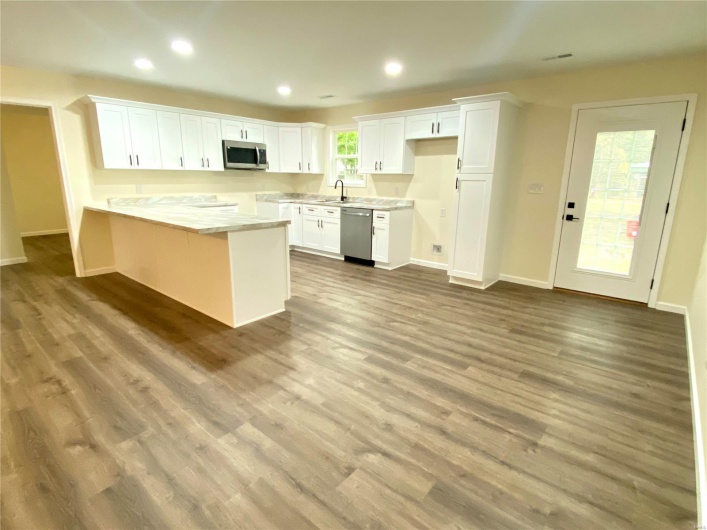 Kitchen with appliances with stainless steel finishes, white cabinetry, and wood-type flooring