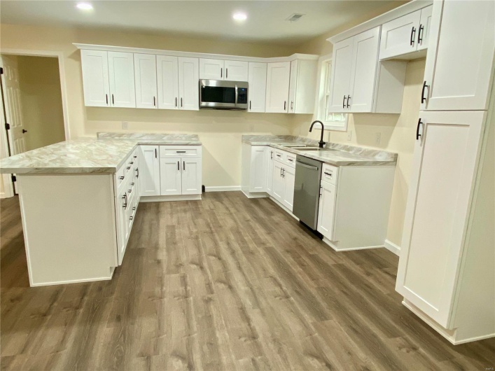 Kitchen with white cabinetry, appliances with stainless steel finishes, and light wood-type flooring