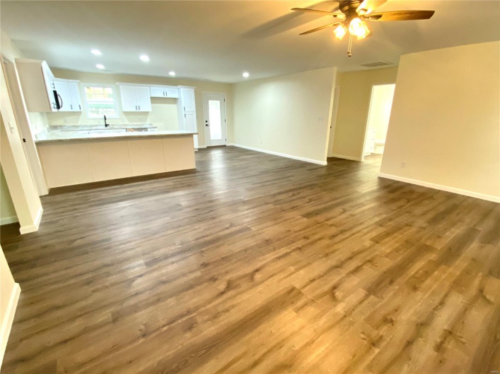 Unfurnished living room featuring sink, ceiling fan, and dark hardwood / wood-style flooring