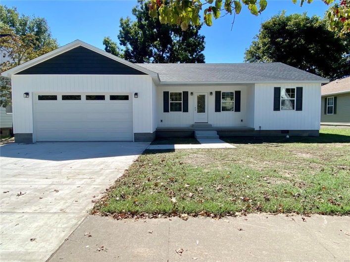 Ranch-style house featuring a garage and a front lawn
