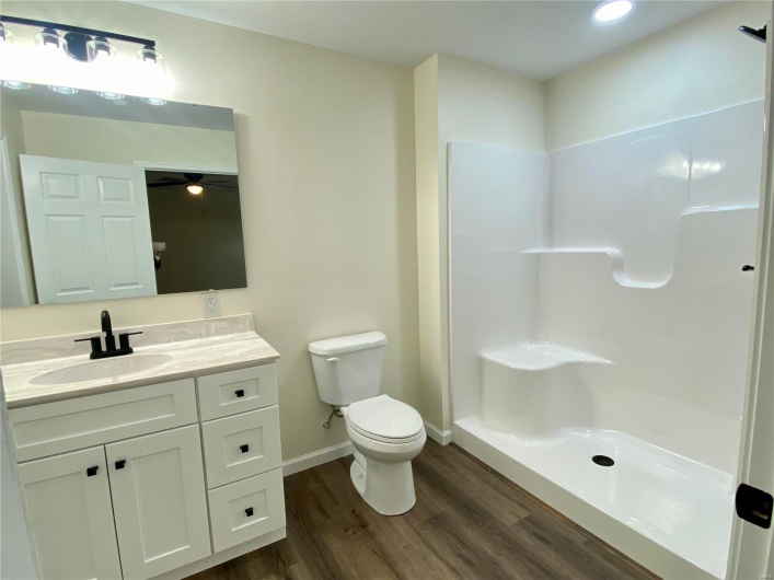 Bathroom featuring vanity, hardwood / wood-style flooring, toilet, and walk in shower