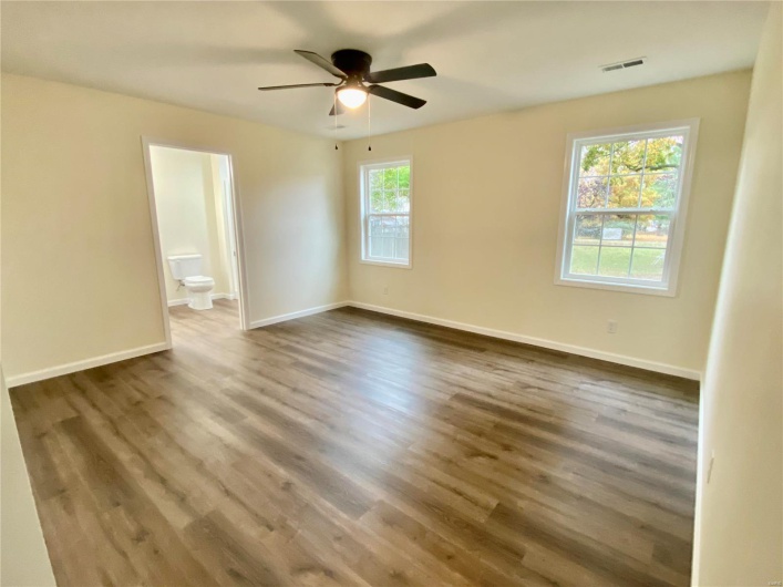 Spare room with a wealth of natural light, dark wood-type flooring, and ceiling fan