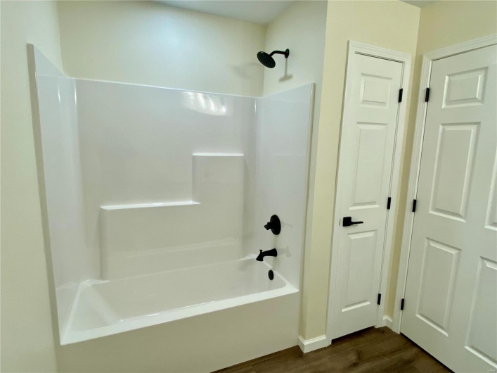 Bathroom with shower / washtub combination and hardwood / wood-style flooring