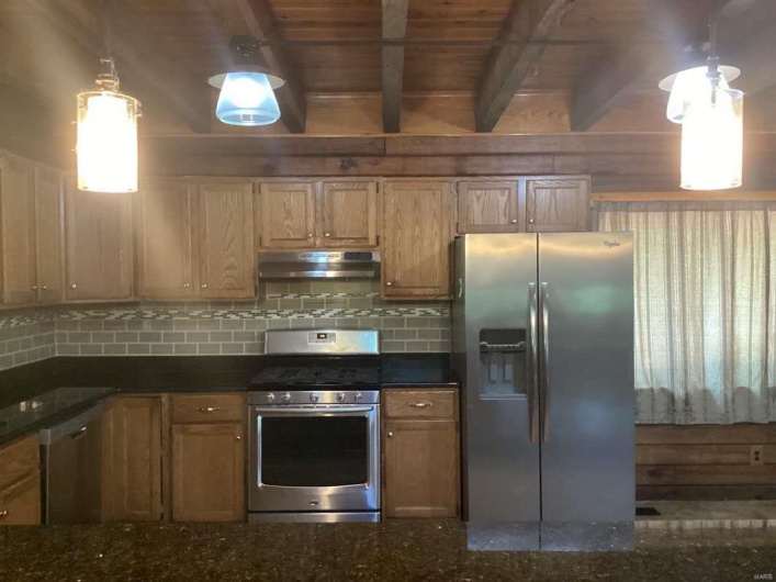 Kitchen with pendant lighting, beamed ceiling, appliances with stainless steel finishes, wooden ceiling, and decorative backsplash