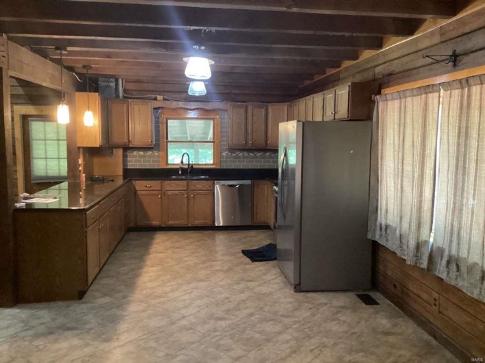 Kitchen featuring hanging light fixtures, sink, stainless steel appliances, and tasteful backsplash
