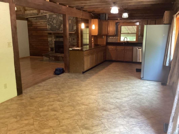 Kitchen with fridge, hanging light fixtures, wooden walls, and sink