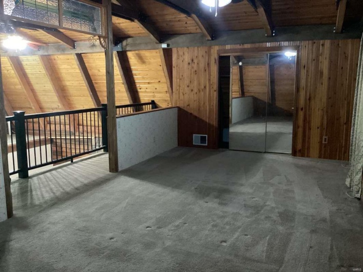 Basement featuring wood ceiling, wooden walls, carpet, and ceiling fan