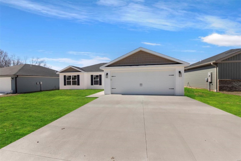 Single story home featuring a garage, driveway, and a front lawn