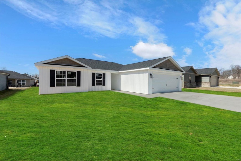 View of front facade featuring a garage, concrete driveway, and a front lawn