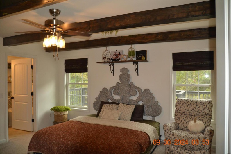 Carpeted bedroom with beamed ceiling and ceiling fan
