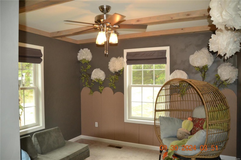 Sitting room featuring carpet, ceiling fan, and beamed ceiling