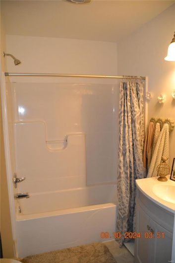 Bathroom with shower / bath combination with curtain and vanity