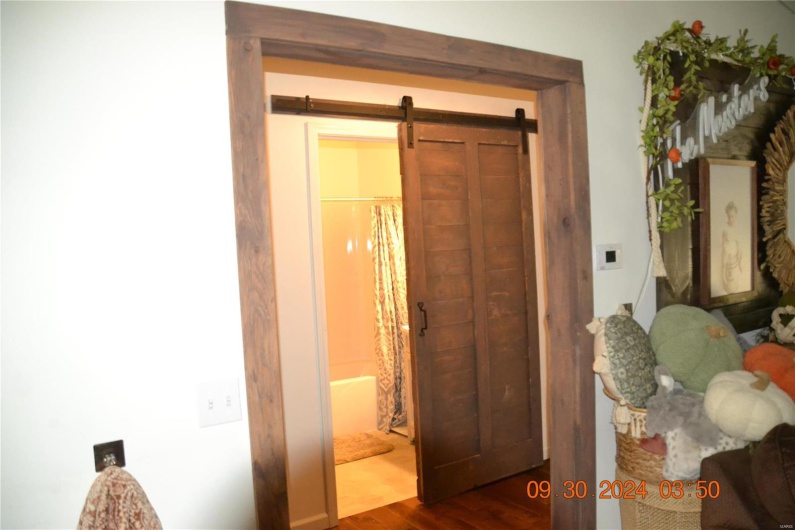 Corridor with wood-type flooring and a barn door