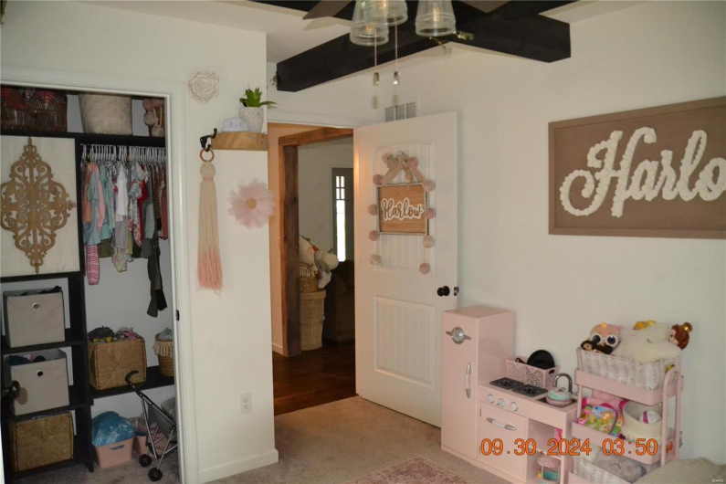 Carpeted bedroom featuring a closet, beamed ceiling, and ceiling fan